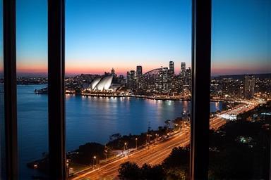 Panoramic view of Sydney skyline from a high-rise atelier window at dusk